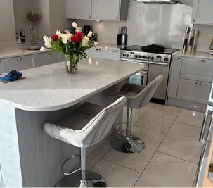A freshly cleaned kitchen with a bright island, bar stools and tulips