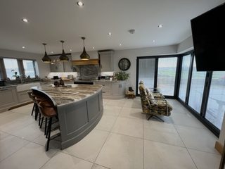 A freshly cleaned open-plan kitchen diner with polished tiled floors and bi-fold doors onto the garden